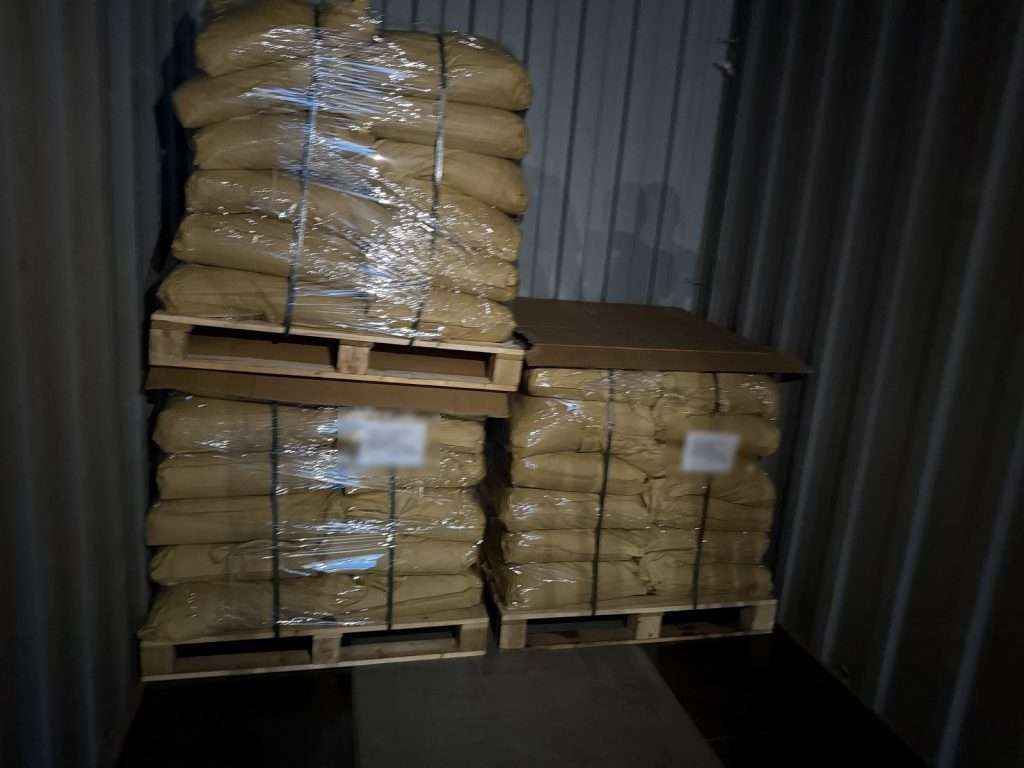 Cardboard sheet between pallet tiers in a lignosulfonate container