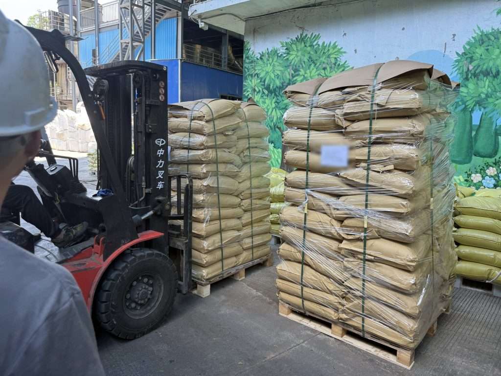 Forklift moving shrink-wrapped pallets of bagged lignosulfonate